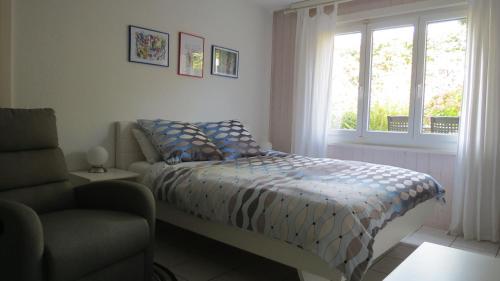 1 dormitorio con cama, ventana y silla en B&B Andrey, en Marly-le-Grand