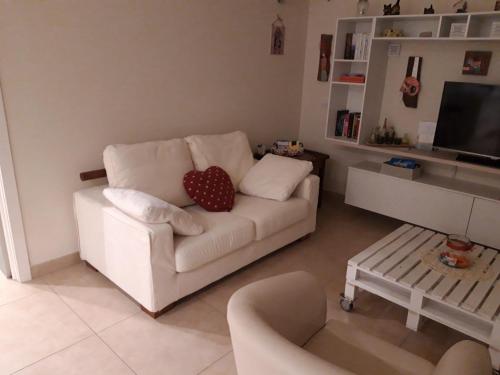ein Wohnzimmer mit einem weißen Sofa und einem Herzkissen in der Unterkunft Nuova casa al lago con piscina in Desenzano del Garda