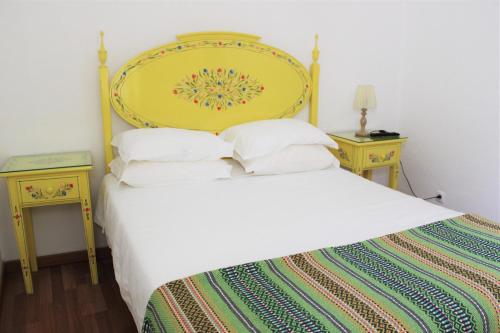 a bedroom with a white bed with a yellow headboard at Mont' Sobro House Rooms in Évora