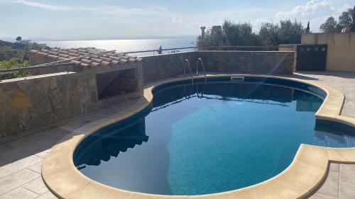 a swimming pool on a patio with the ocean in the background at Villa familiale piscine privée et magnifique vue mer in Roses