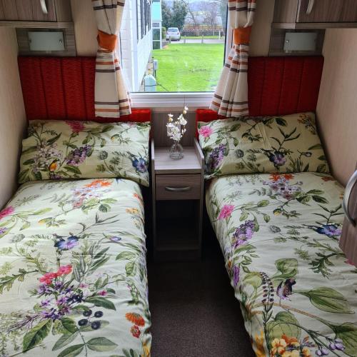two beds in a small room with a window at Oscars caravan in Abergele