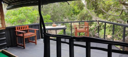 a balcony with two chairs and a table and a table at Jungle Cabin in Bundala Levagamgoda