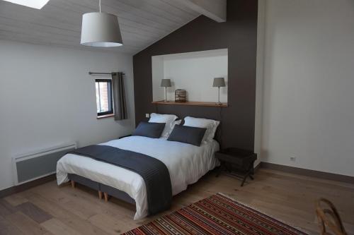 um quarto com uma cama com lençóis brancos e almofadas azuis em Un Air de Campagne - Gîtes 4 étoiles em Beauzelle