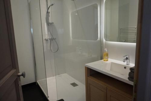 uma casa de banho branca com um chuveiro e um lavatório. em Un Air de Campagne - Gîtes 4 étoiles em Beauzelle