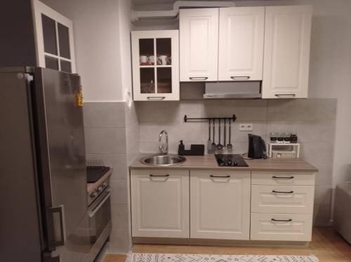 a kitchen with white cabinets and a stainless steel refrigerator at DAMI in Tuzla