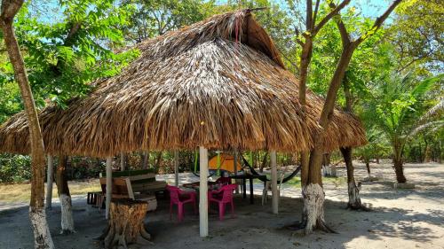 una cabaña con una mesa y sillas debajo en Eco-Camping El Frutal, en Isla Grande