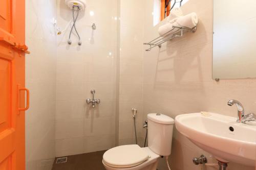 a white bathroom with a toilet and a sink at Teles Westend Hotel in Marmagao
