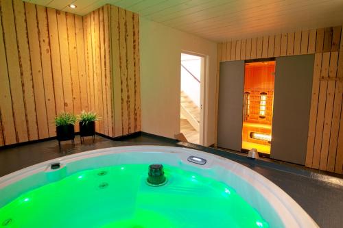 Habitación con baño con bañera verde. en Jacuzzi & Sauna Villa, en Tzummarum