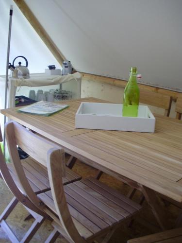 - une table en bois avec une bouteille de verre vert dans l'établissement Ferme Rony Camp des Découvreurs, à Saint-Nizier-du-Moucherotte