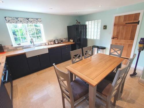 uma cozinha com uma mesa de madeira, uma mesa e cadeiras em Countryside 3 Bed Detached Cottage em Royal Wootton Bassett