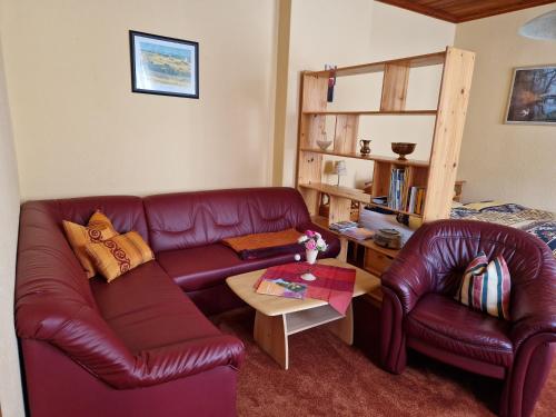- un salon avec un canapé et des fauteuils en cuir rouge dans l'établissement Ferienwohnung Matthisson, à Oranienbaum-Wörlitz