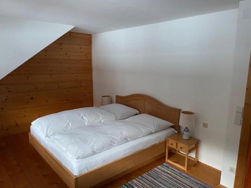 Una cama con sábanas blancas en una habitación con escalera. en Apartment Lindbichler, en Bad Hofgastein