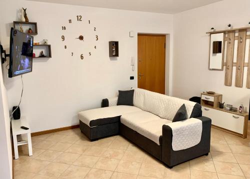 uma sala de estar com um sofá e um relógio na parede em Top Apartment 2 em Castel d'Azzano