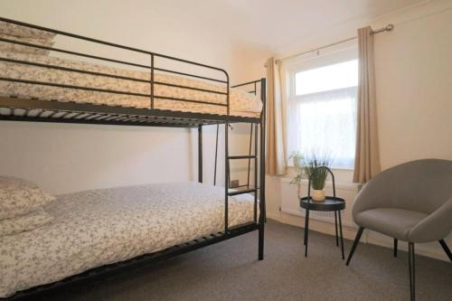 1 dormitorio con 2 literas y 1 silla en Cute Central Georgian Cottage en Hastings