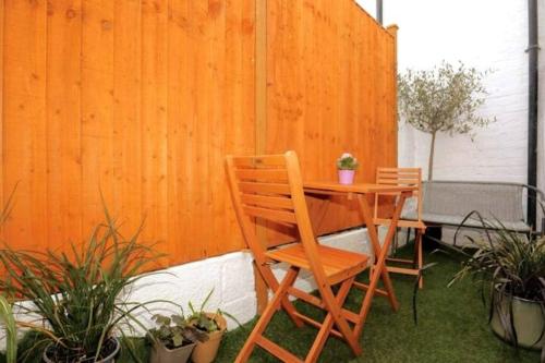a wooden table and chairs on a patio with plants at Cute Central Georgian Cottage in Hastings
