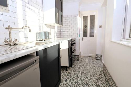 a white kitchen with a sink and a counter at Cute Central Georgian Cottage in Hastings