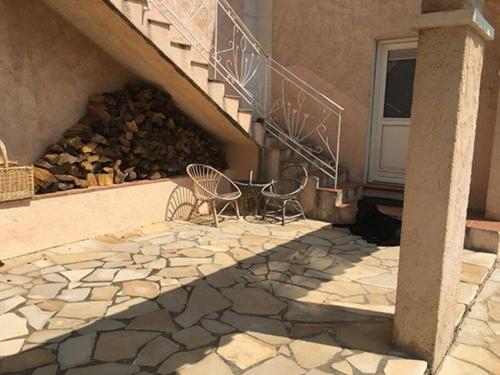 a patio with two chairs and a pile of fire wood at Experience the Provençal dream in Taradeau