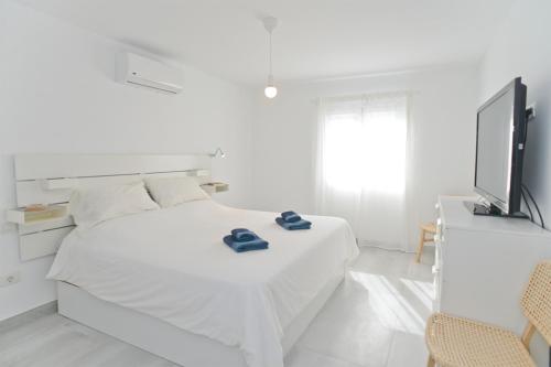 a white bedroom with a bed and a flat screen tv at Luxury Buenavista Famara in Famara