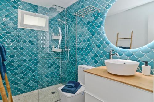 a bathroom with a sink and a shower with blue tiles at Luxury Buenavista Famara in Famara