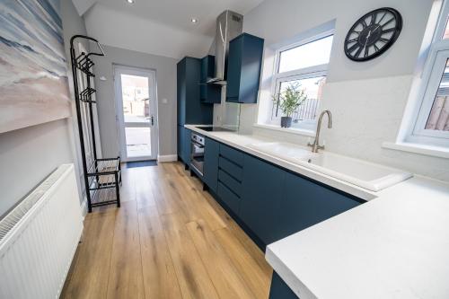 a kitchen with blue cabinets and a sink and a window at Highgate Beach House - Great for family stays and contractors in Cleethorpes