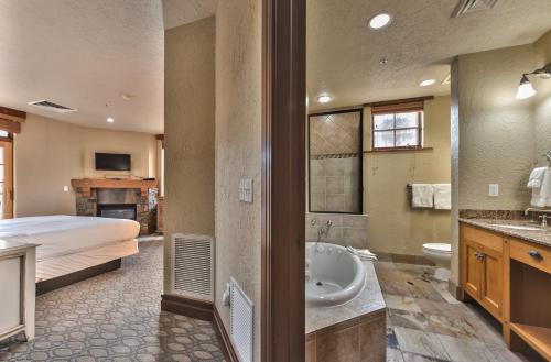 - une chambre avec un lit et une salle de bains pourvue d'une baignoire dans l'établissement 2BR Ski-in-Out Condo With Pool MC6B, à Park City