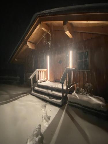 a cabin with snow on the stairs and lights at Almhütte in Lachtal
