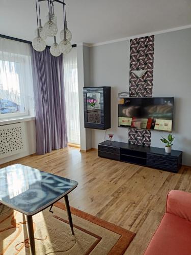 een woonkamer met een tafel en een televisie bij Apartament Willamore in Szczecin