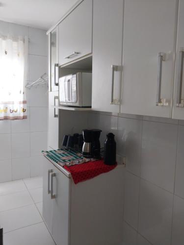 uma cozinha com armários brancos e um forno com placa de fogão em Apto Richard Shopping em Campos dos Goytacazes