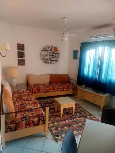 ein Wohnzimmer mit einem Sofa und einem Tisch in der Unterkunft Appartamento Calarossa Sardegna CasaRosa in Isola Rossa