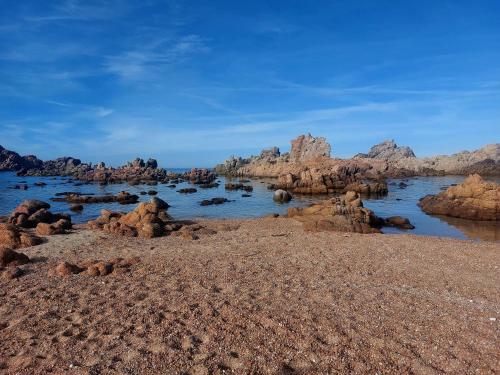 a rocky beach with rocks in the water at Appartamento Calarossa Sardegna CasaRosa in Isola Rossa