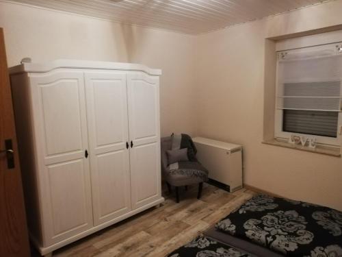 a bedroom with a white cabinet and a chair at Haus Oldenburg in Lauterecken