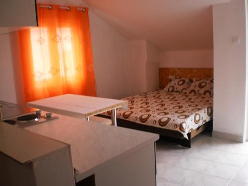 a small bedroom with a bed and an orange curtain at Apartments Odzic in Tivat