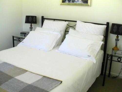 Glen Waverly Farmstay في غلين اينيس: غرفة نوم بسرير ذو شراشف ووسائد بيضاء