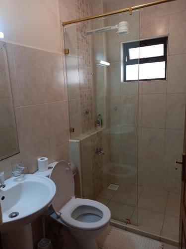 a bathroom with a shower and a toilet and a sink at Westpoint Suites by Senga in Nairobi