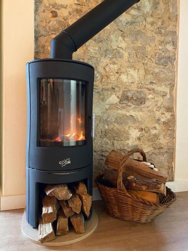 a wood burning stove with a basket of logs at Casinha da Avó Rosário in Juncal