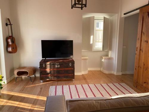 a living room with a flat screen tv on a dresser at Casinha da Avó Rosário in Juncal