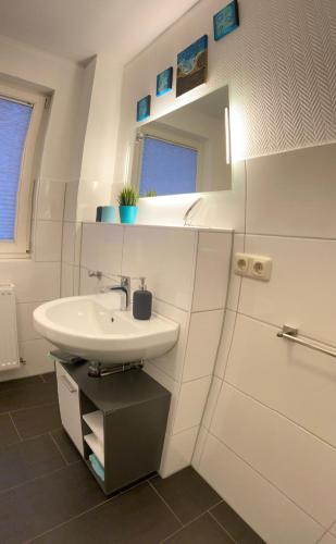 ein weißes Badezimmer mit Waschbecken und Spiegel in der Unterkunft Susi's Seeblick in Waren (Müritz)
