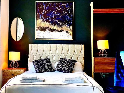 a bedroom with a bed with two lamps and a painting at Duke and Duchess Apartments and Rooms - Private in Room Hot Tub Suites in London