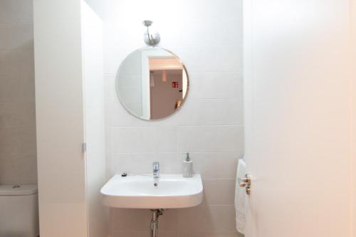 a white bathroom with a sink and a mirror at Telmo's Home con PARKING in Zumaia