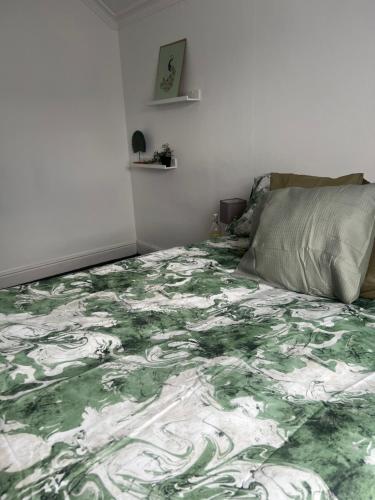 a bedroom with a bed with a green and white blanket at Spacious family home in Cardiff
