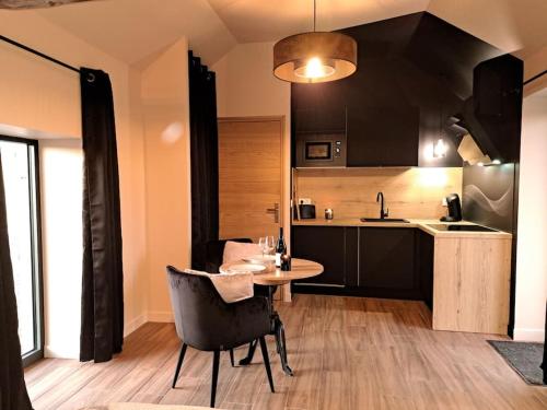 eine Küche mit einem Tisch und Stühlen im Zimmer in der Unterkunft La bergerie cosy - Sauna et bain nordique privatif in Saint-Denis-de-Jouhet