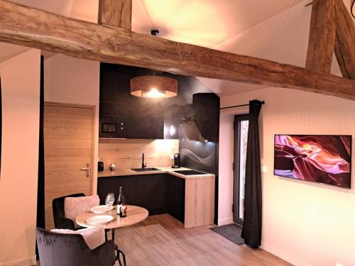 Zimmer mit einem Tisch und einer Küche mit einer Theke in der Unterkunft La bergerie cosy - Sauna et bain nordique privatif in Saint-Denis-de-Jouhet