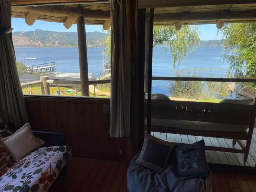 a room with a large window with a view of the water at Maravillosa cabaña en orilla de Lago Vichuquén in El Rodeo