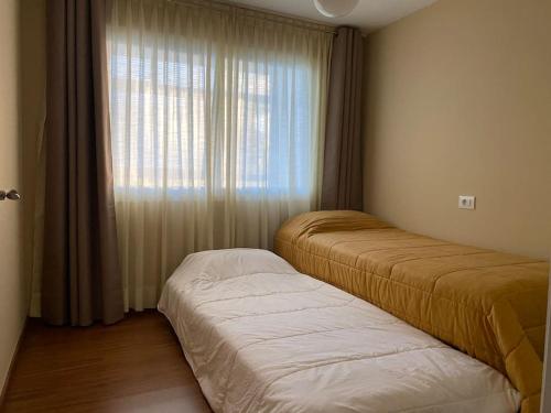 1 dormitorio con 2 camas y ventana en Río, mar y montaña en Puentedeume