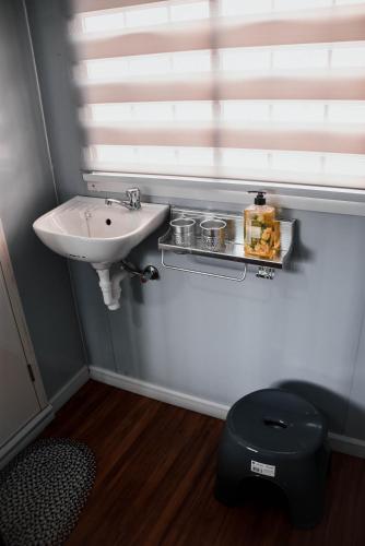 a bathroom with a sink and a toilet and a window at Olive Hostel Roxas City in Roxas City