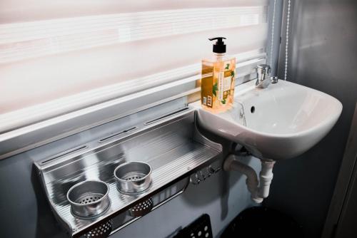 a bathroom with a sink and two measuring cups at Olive Hostel Roxas City in Roxas City