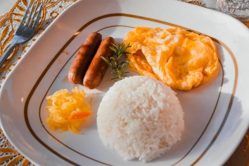 a plate of food with rice and eggs and meat at Olive Hostel Roxas City in Roxas City