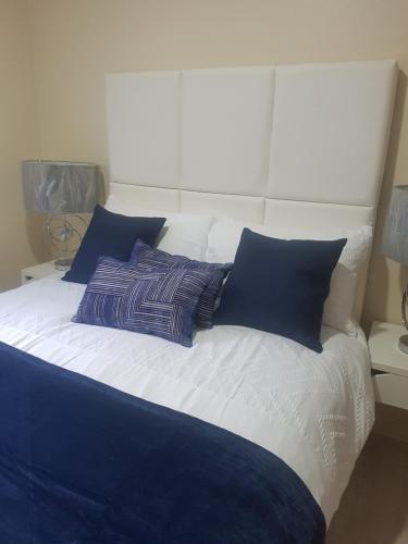 a bed with blue and white pillows on it at Dunoon Gourock Inverkip Apartment in Gourock