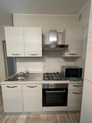 a kitchen with white cabinets and a stove top oven at Piccola residenza del parco in Quartucciu