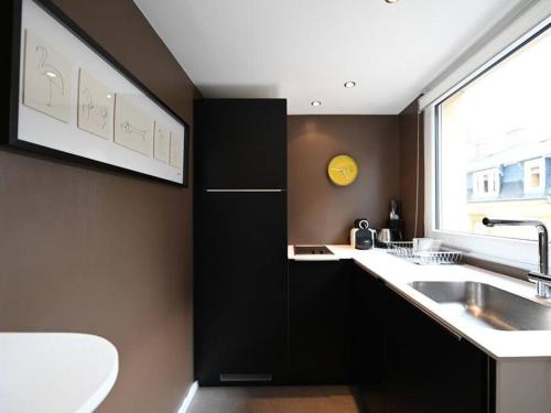a kitchen with black cabinets and a sink and a window at Limpersberg - Amazing and cozy flat in Luxembourg